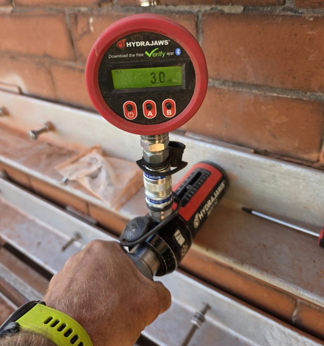 Engineer pull testing an anchor fixing with a digital gauge