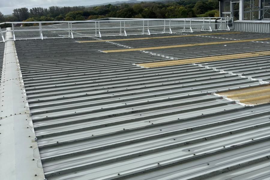 Free-standing guardrail along the edge of a profiled metal roof